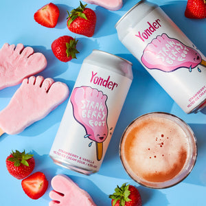 Yonder strawberry and vanilla ice cream sour cans with strawberries and pink ice cream on a blue background